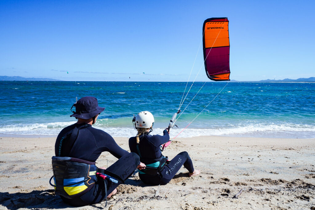 two people beeing at the beach, flying a kite